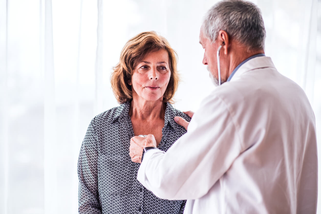 Male doctor examiming a senior woman in his office