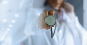 Doctor holding a stethoscope towards the camera, representing what to ask an internal medicine doctor.