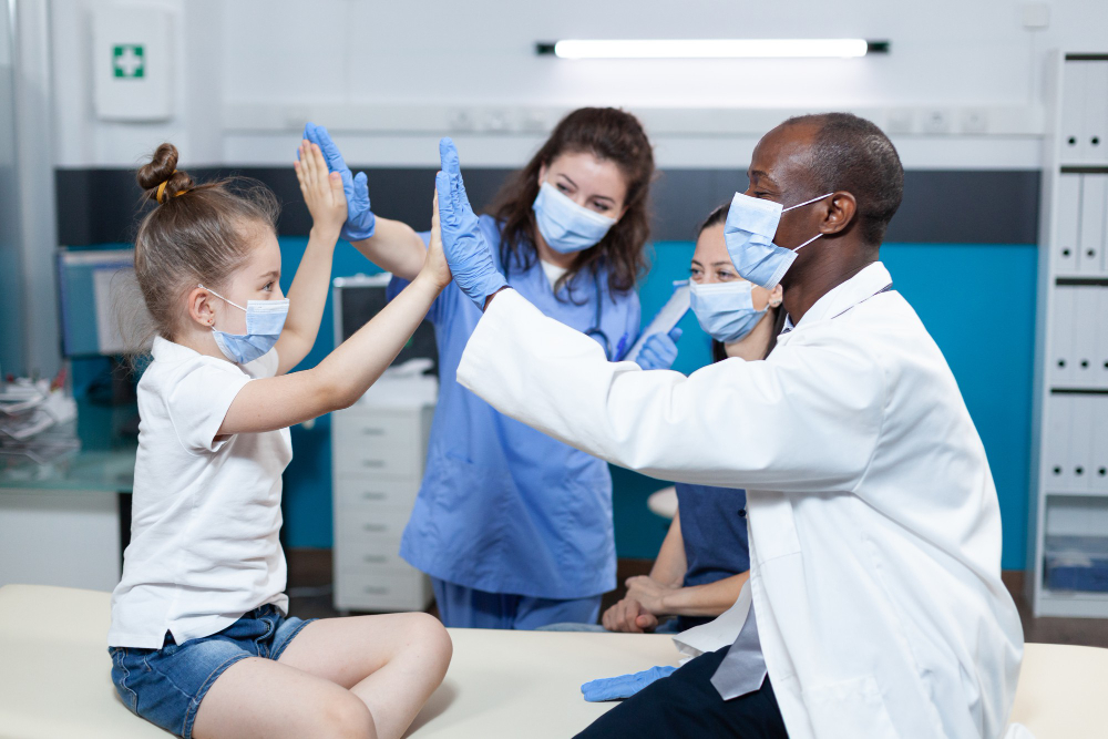 a doctor and nurse high-fives a school girl for her back-to-school physical exam