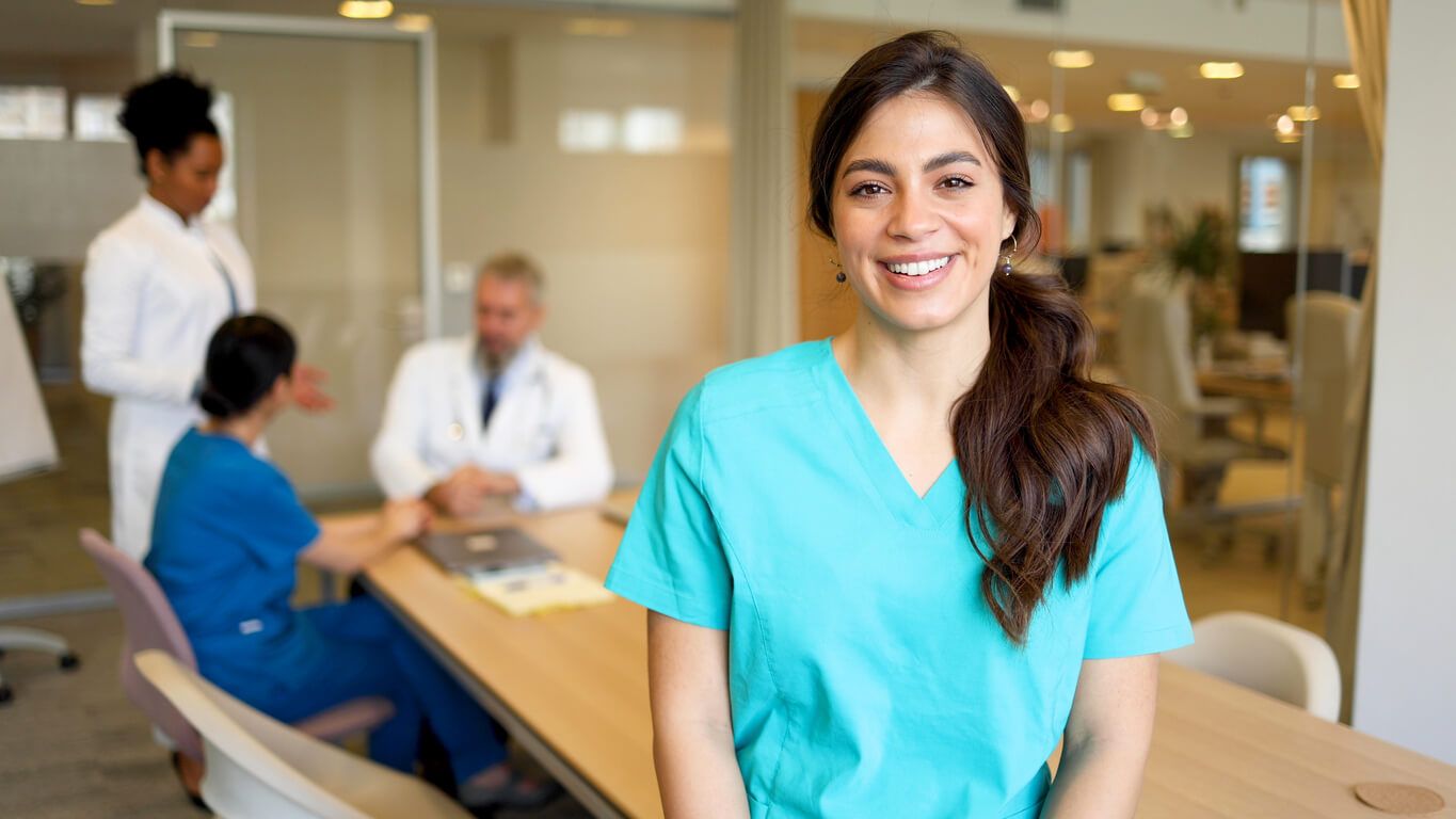 Portrait of a smiling young nurse attending a medical team meeting at the hospital conference room