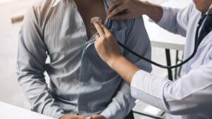 man getting a preventative health screenings by a doctor checking his heartbeat