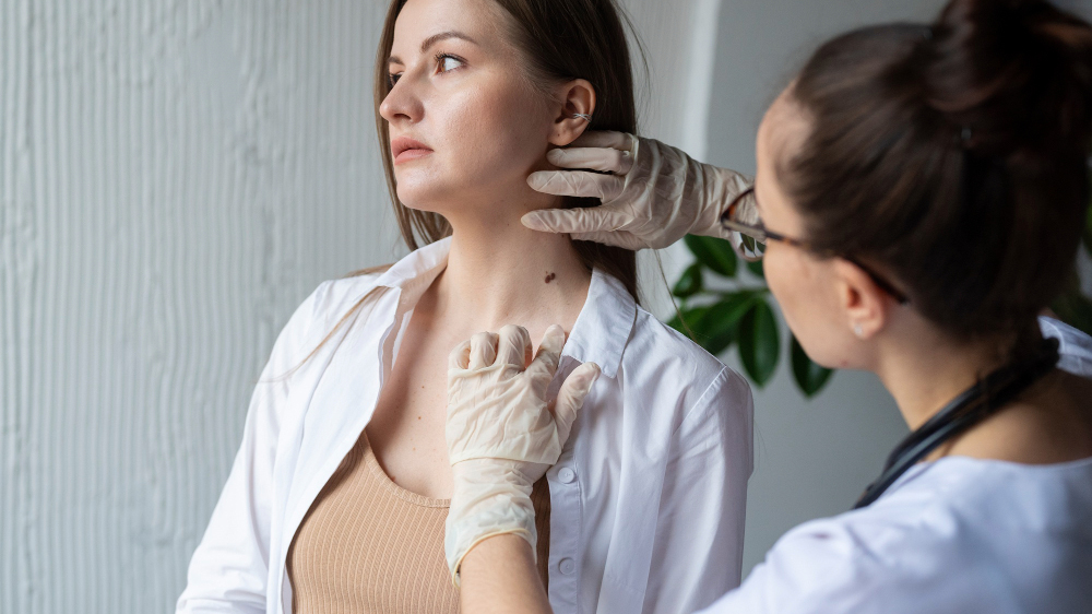 a female doctor performing a mole check on a female patient's neck