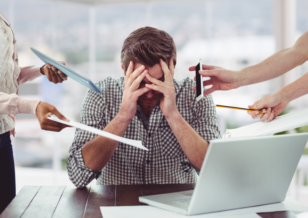 Overwhelmed office worker at a laptop, showing how stress and physical health can be affected.
